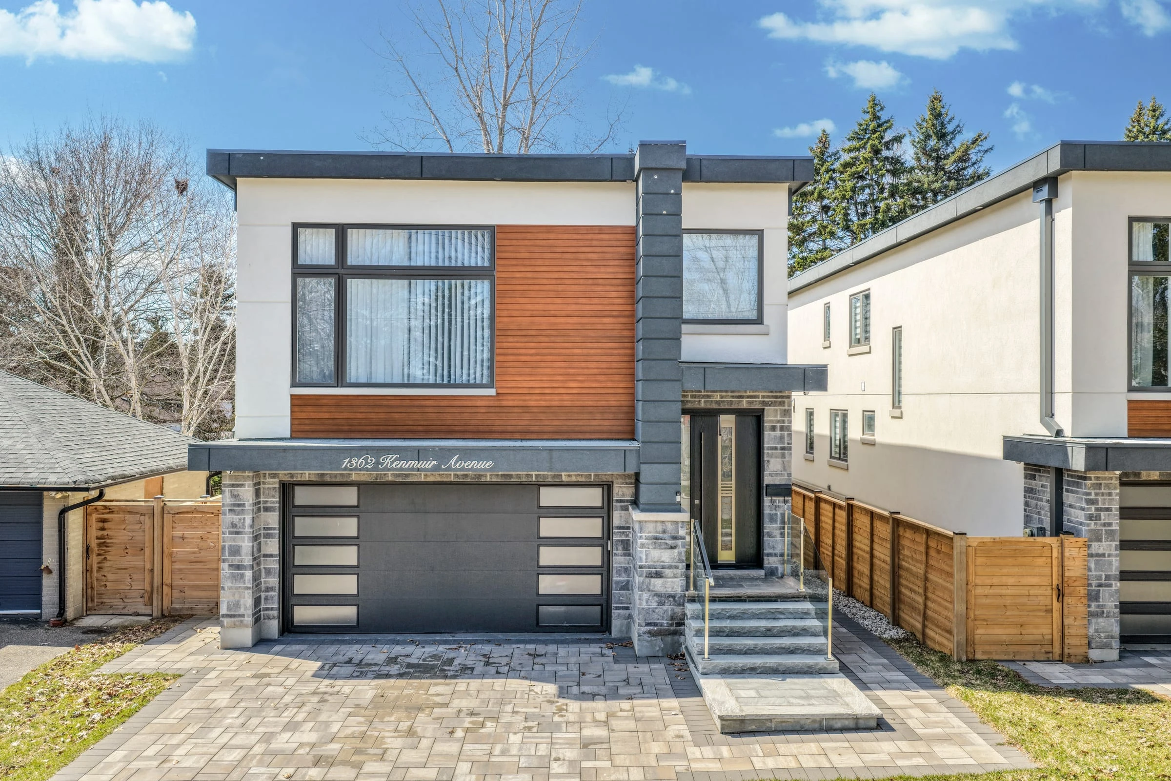 Aerial drone photograph of a modern two-storey custom home in Mississauga with paver driveway and glass-panel entrance