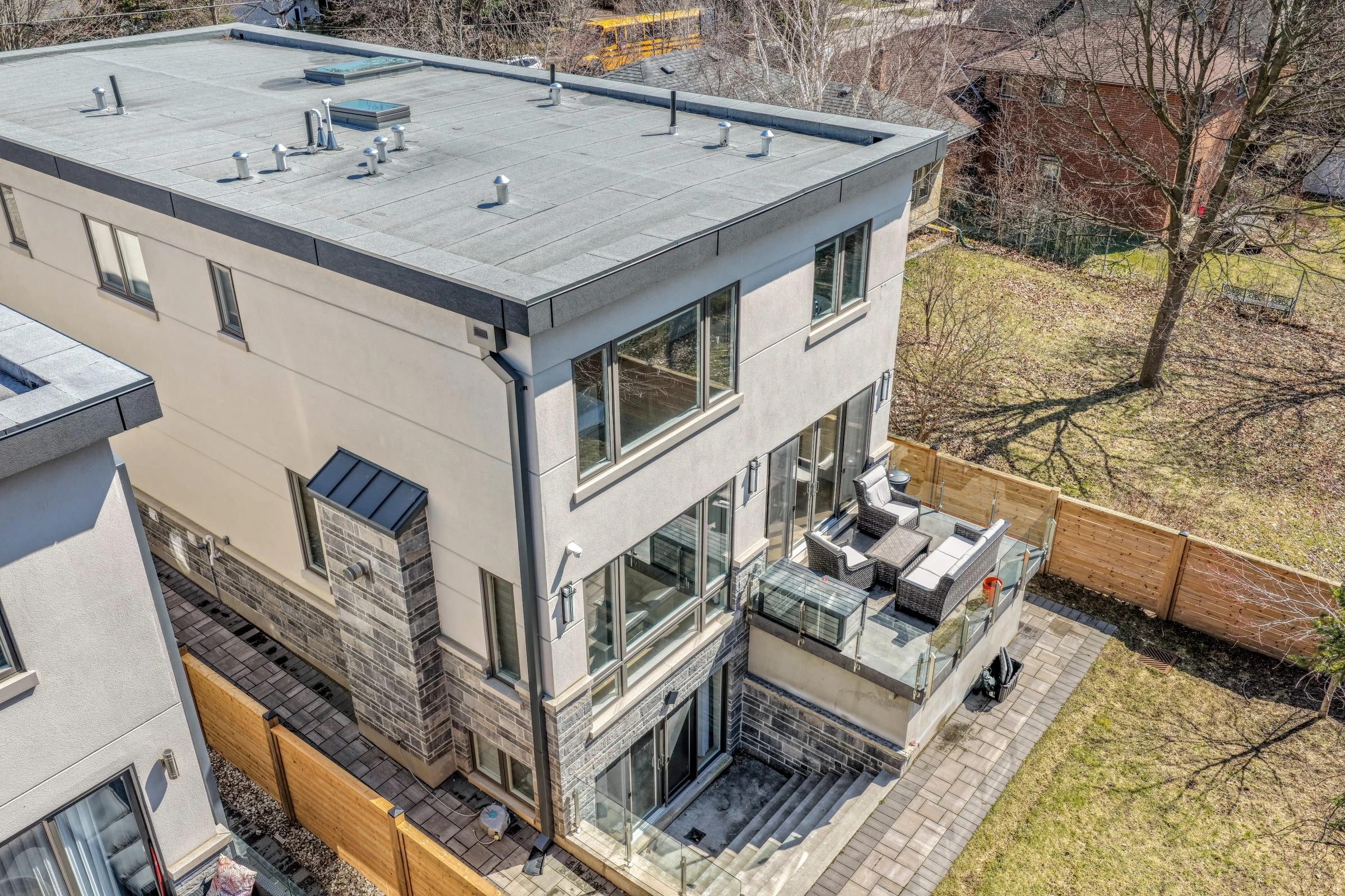 Close aerial drone photograph of a rear terrace, glass railings and outdoor seating area - RCG Canada