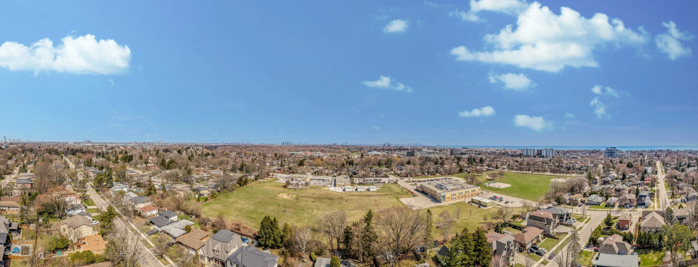 Wide aerial drone photograph over a Mississauga neighbourhood with the Toronto skyline on the horizon