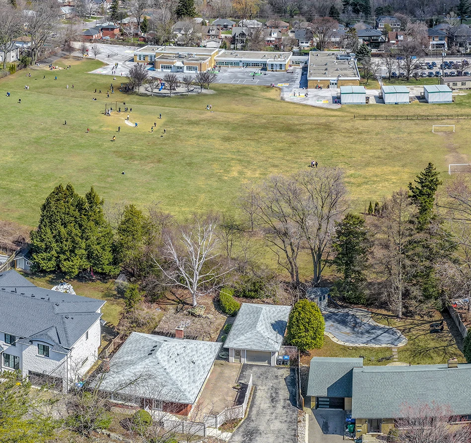 Aerial drone photograph looking down over the bungalows behind a Kenmuir Avenue property in Mississauga, with the neighbouring school field and playground beyond. RCG Canada real estate photography