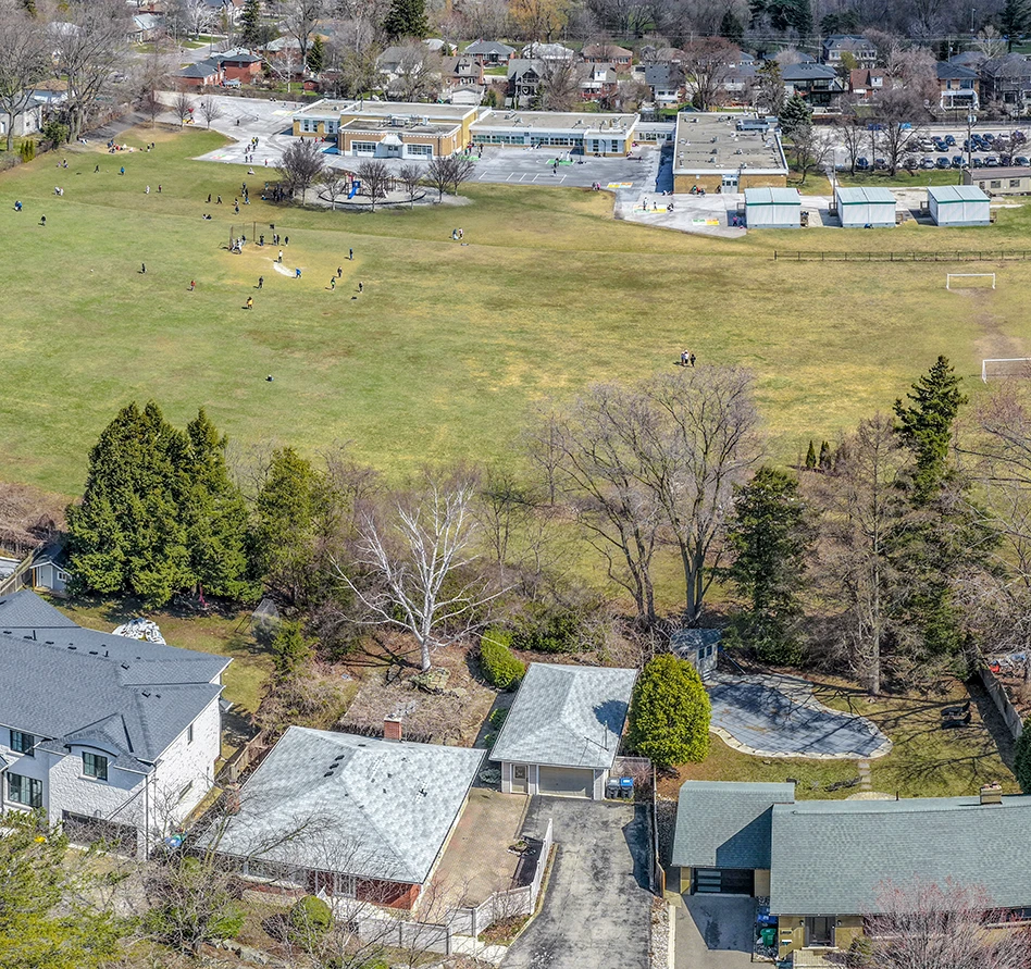 Aerial drone photograph over the bungalows behind a Kenmuir Avenue property, school field beyond - RCG Canada