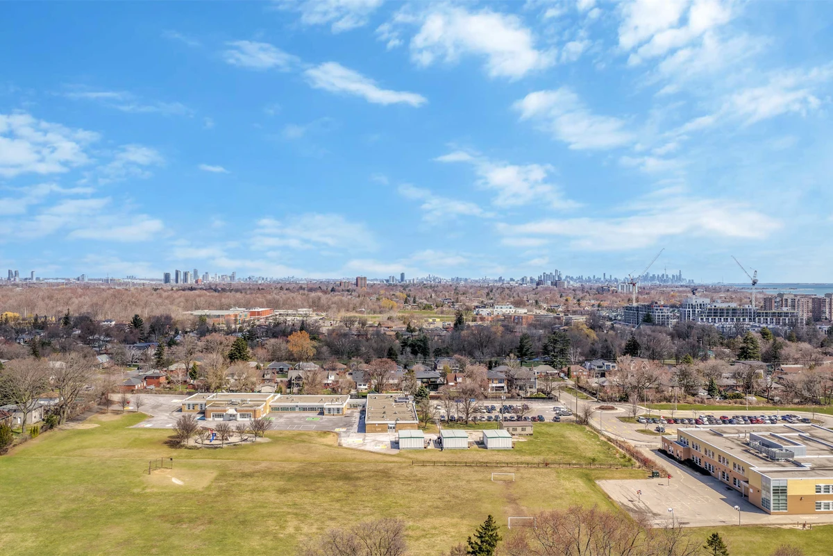High panoramic aerial drone photograph across Mississauga rooftops and open parkland toward the downtown Toronto skyline on the horizon. RCG Canada real estate photography