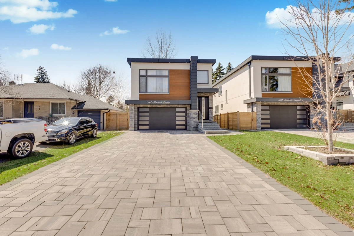 Exterior photograph of a modern Mississauga home from the foot of its paver driveway, flat roofline and glass entry door in full daylight. RCG Canada real estate photography