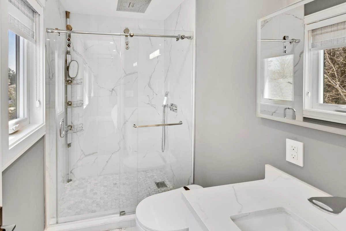 Sleek secondary bathroom with a frameless glass shower, marble-look tile and quartz vanity in a Mississauga home. RCG Canada interior photography