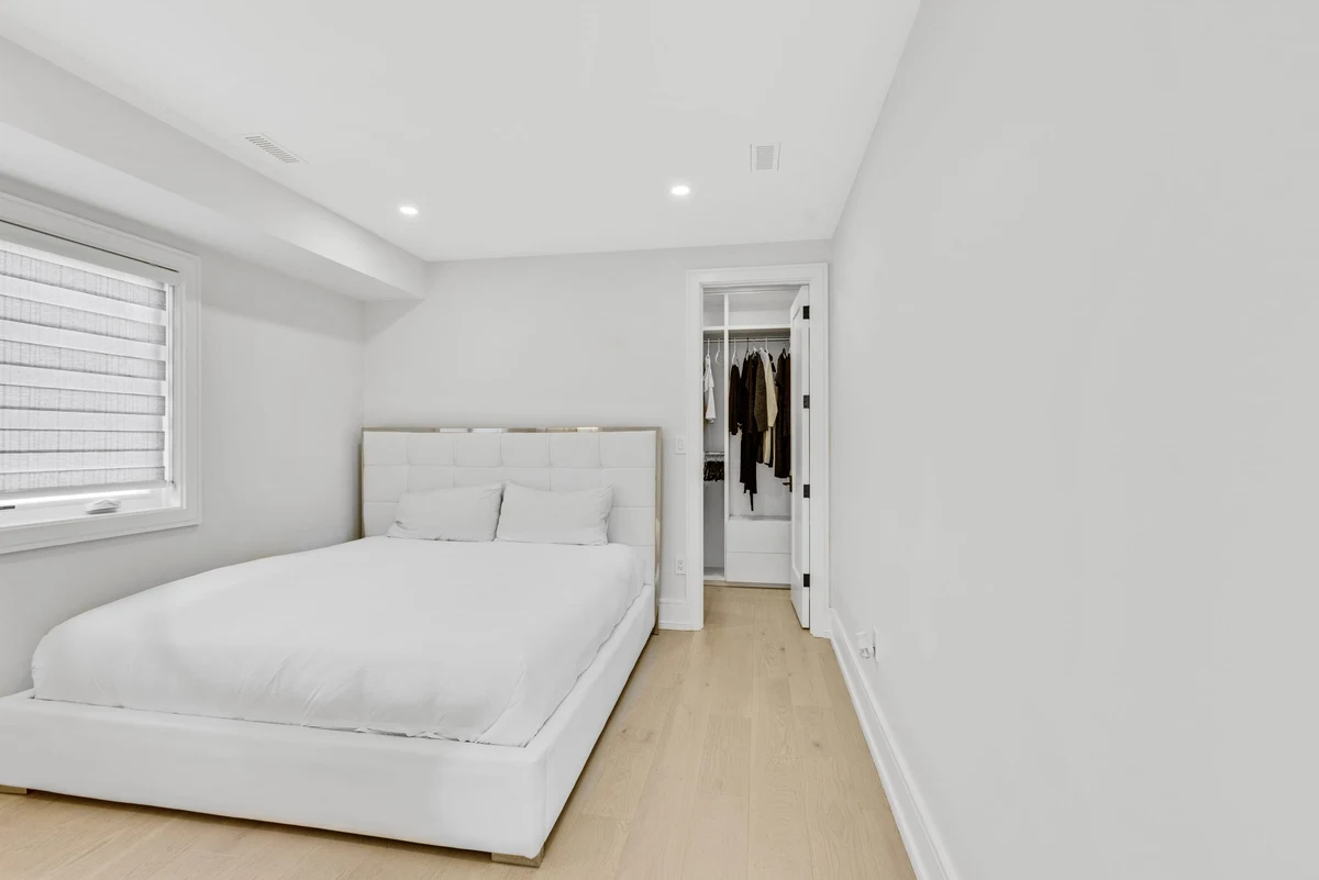 Crisp white guest bedroom with a tufted headboard and walk-in closet in a Mississauga home. RCG Canada interior photography
