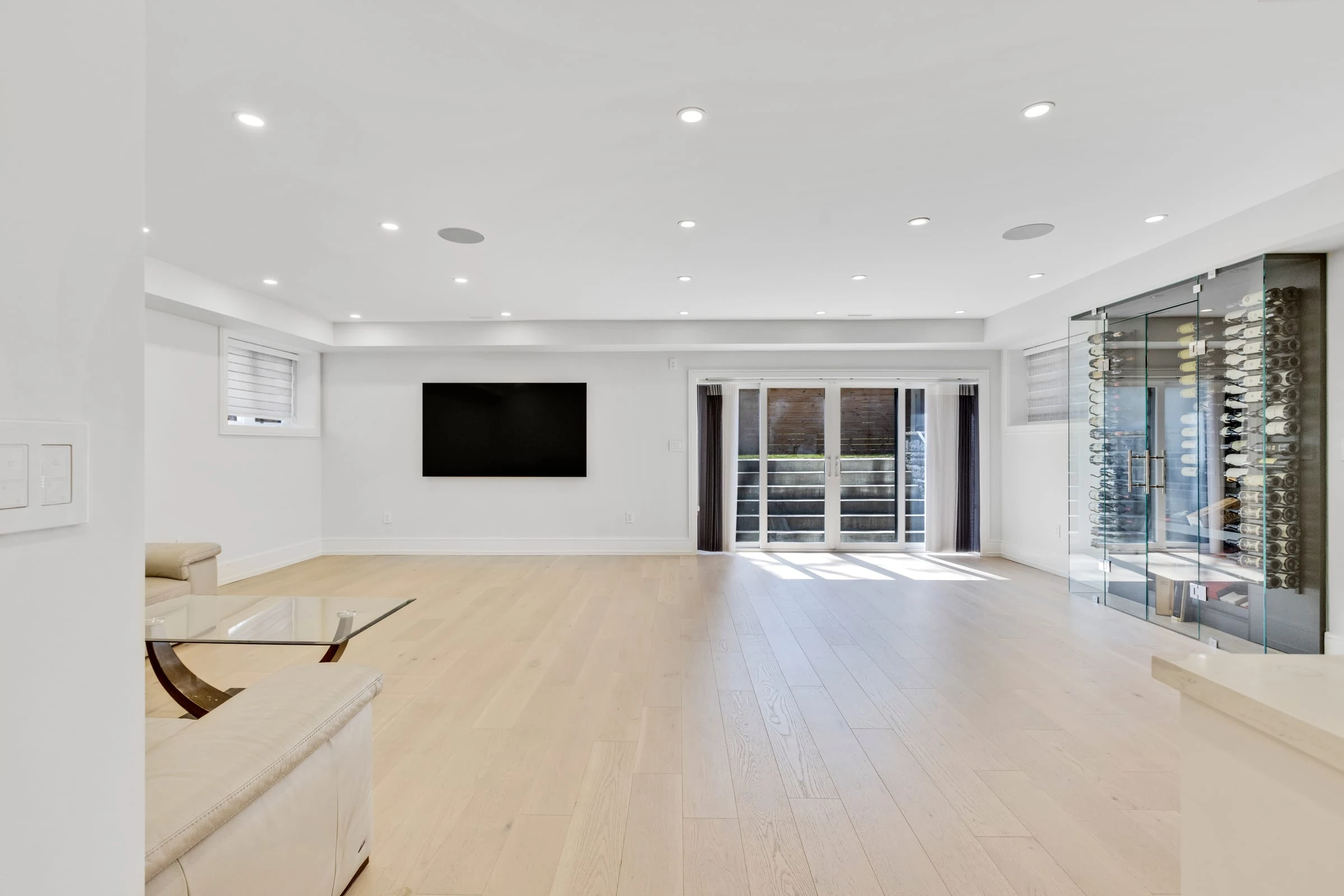Finished lower-level recreation room with a glass-enclosed wine cellar and walkout to the backyard - RCG Canada