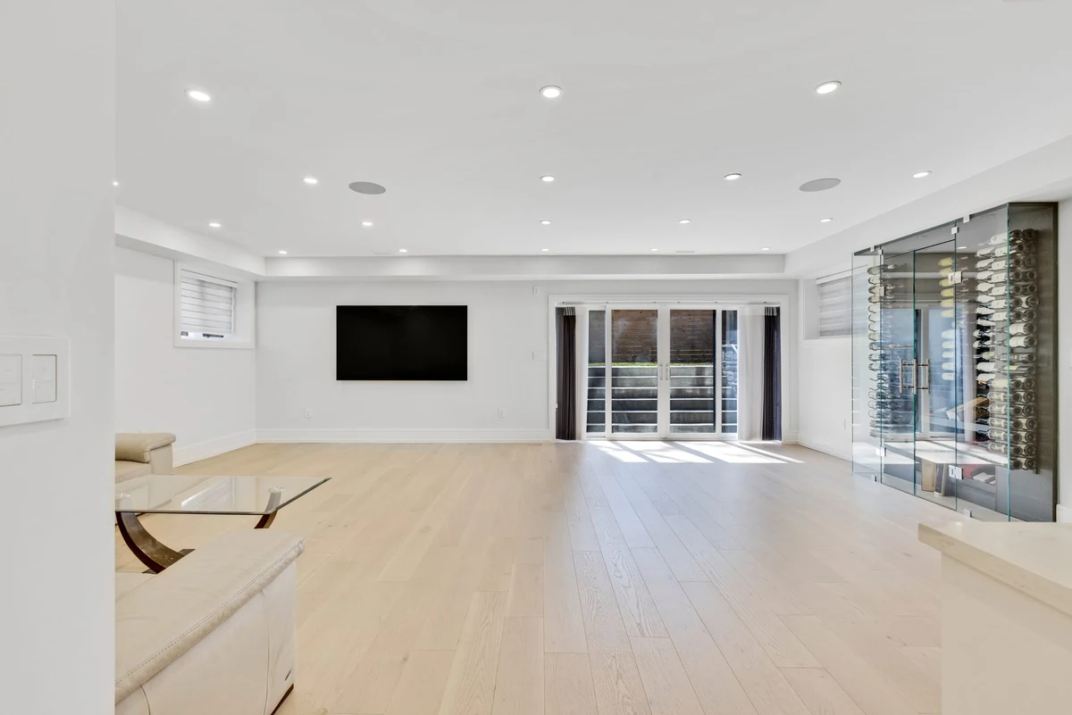 Finished lower-level recreation room with a glass-enclosed wine cellar and walkout to the backyard in a Mississauga home. RCG Canada interior photography