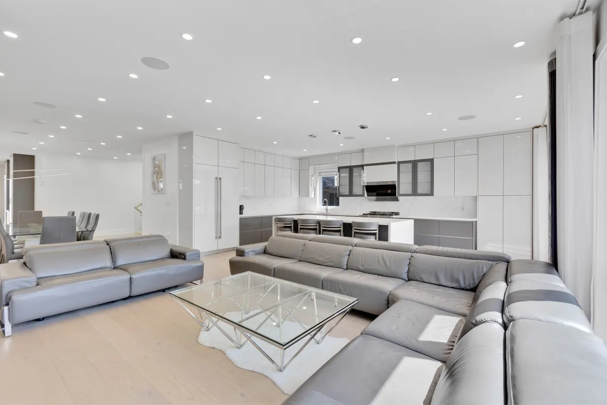 Wide open-concept great room in a Mississauga home, twin sofas facing a high-gloss kitchen, the kind of space a Matterport tour is captured in