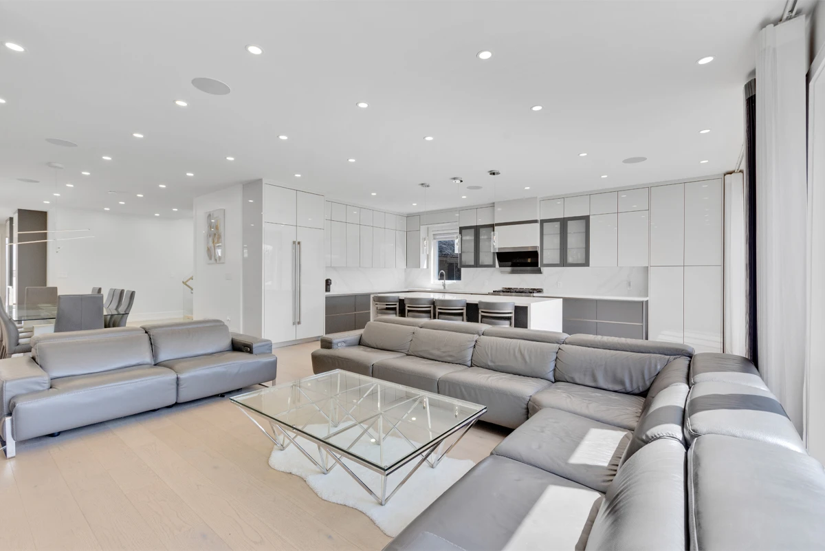 Wide open-concept great room in a Mississauga home, twin sofas facing a high-gloss kitchen, the kind of space a Matterport tour is captured in