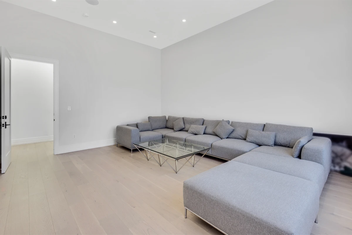 Minimal sitting room with a grey L-shaped sectional and wide-plank oak flooring - RCG Canada