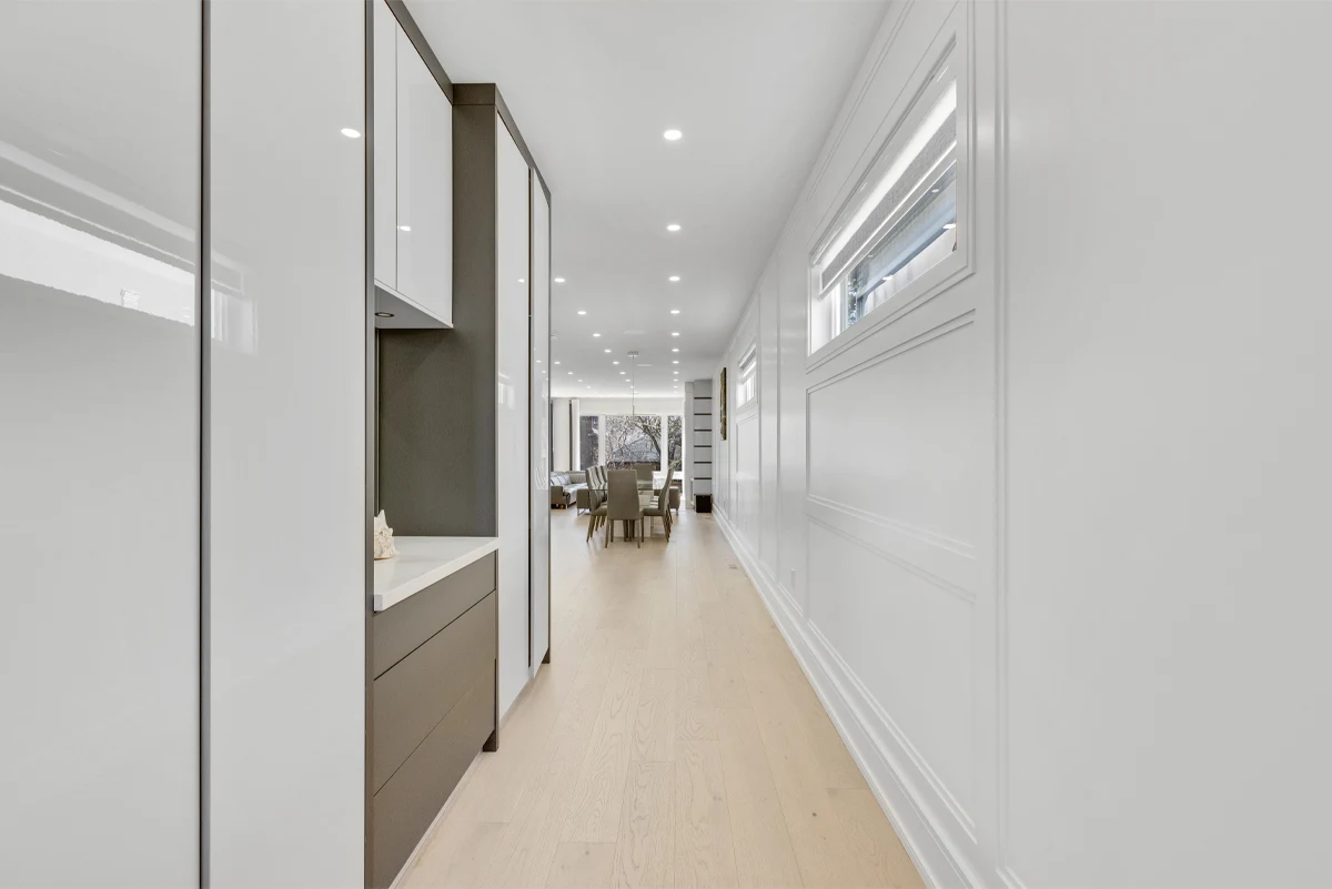Long entry corridor with wainscoted panelling and built-in cabinetry leading to the dining area of a Mississauga home. RCG Canada interior photography