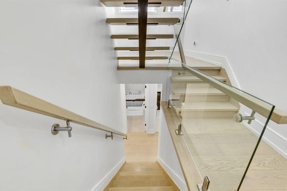 Overhead view of the multi-level open-tread staircase and oak handrail connecting three floors - RCG Canada