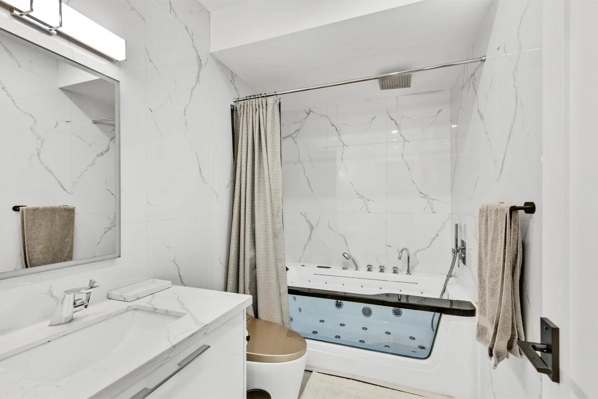 Marble-clad bathroom with a jetted soaker tub, overhead rain shower and floating vanity in a Mississauga home. RCG Canada interior photography