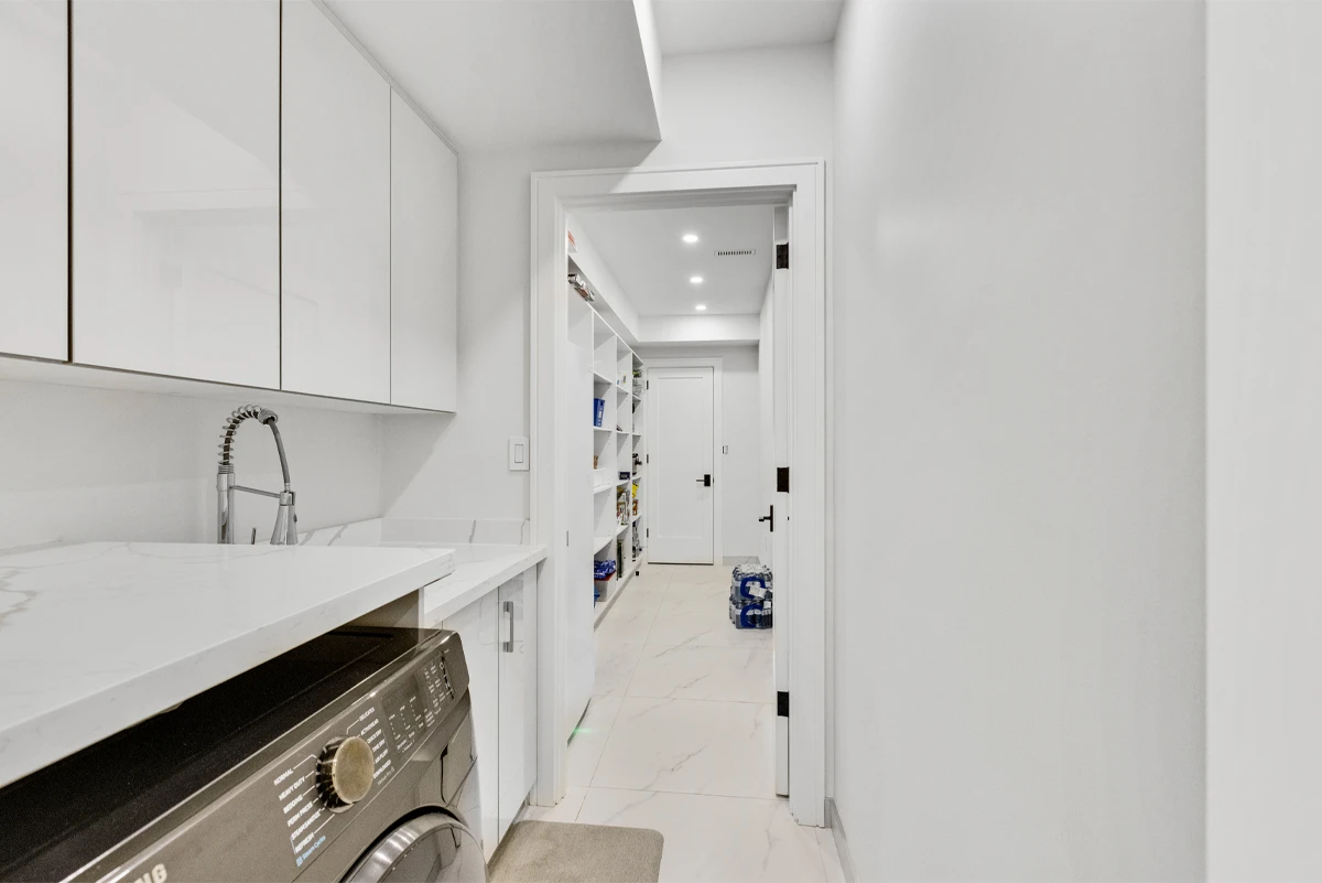 Laundry room with high-gloss cabinetry, a quartz folding counter and utility sink beside the pantry - RCG Canada