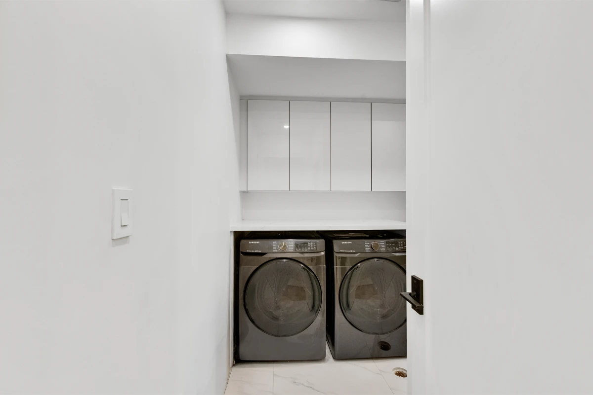 Concealed laundry nook with a side-by-side washer and dryer under a quartz counter - RCG Canada